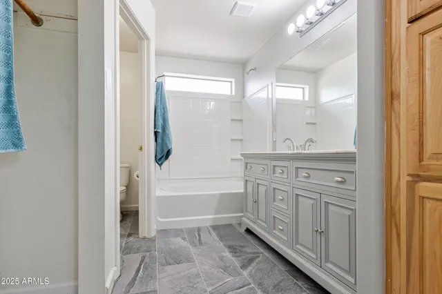 a bathroom with a granite countertop sink a mirror and a bathtub