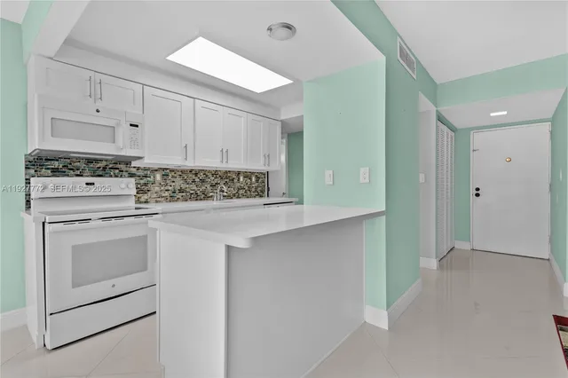 a kitchen with white cabinets and white appliances