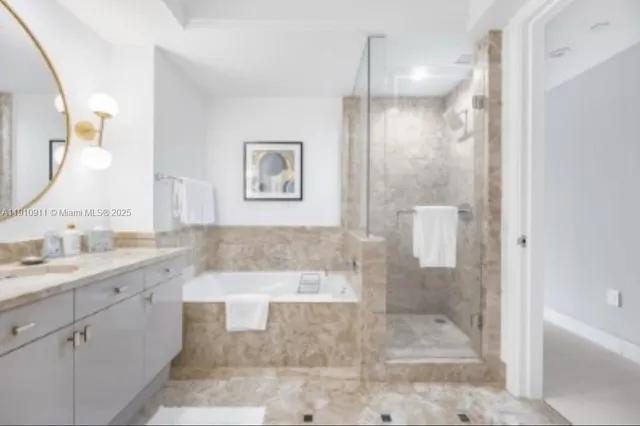 a bathroom with a granite countertop sink a mirror a bathtub and shower