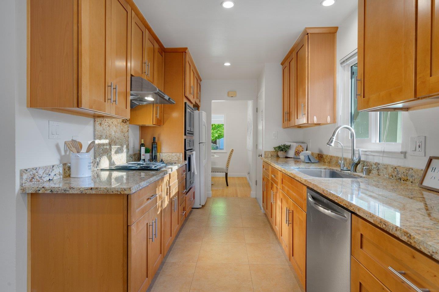 7457 Rollingdell Drive Cupertino, CA 95014 - Photo 12 of 33 a kitchen with stainless steel appliances granite countertop a sink a stove and a wooden cabinets