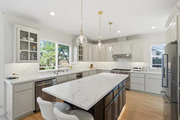 a kitchen with stainless steel appliances granite countertop a sink a stove a refrigerator a center island and a window