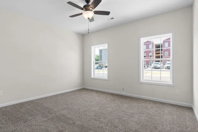 an empty room with windows and fan