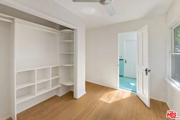 a view of an empty room with wooden floor and closet