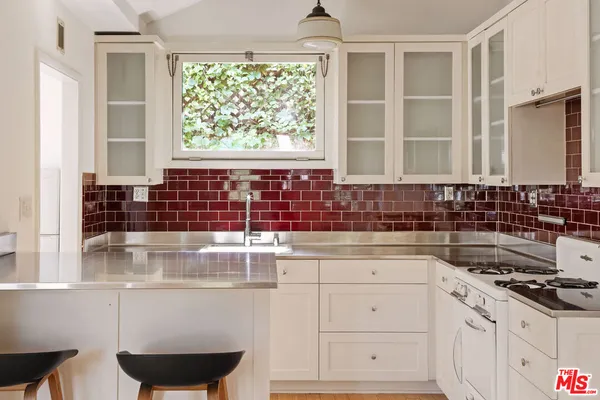 a kitchen with a sink a stove and white cabinets