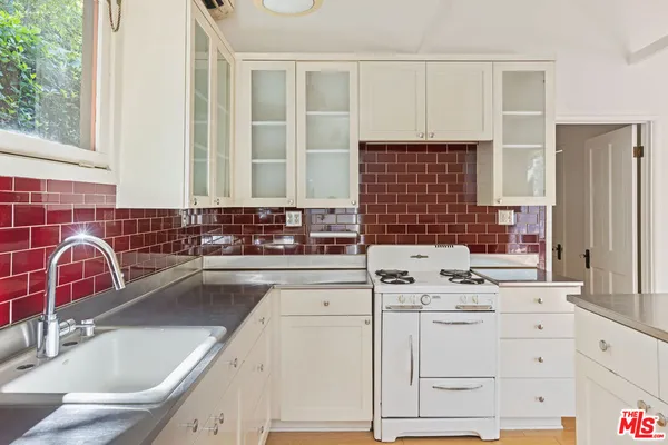 a kitchen with cabinets appliances a sink and a window