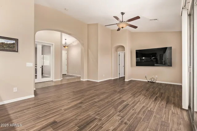 a view of empty room with wooden floor and fan
