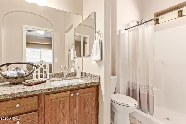 a bathroom with a granite countertop sink a mirror and a shower