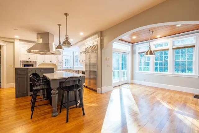 a dining hall with stainless steel appliances kitchen island granite countertop a table chairs and a large window