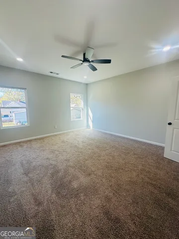 an empty room with windows and ceiling fan