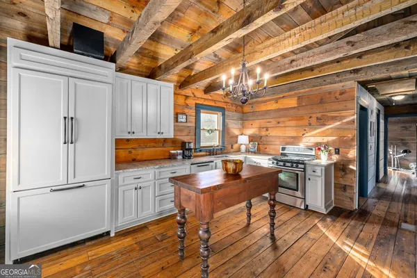 a kitchen with stainless steel appliances granite countertop a refrigerator a sink dishwasher a stove and white countertops with wooden floor