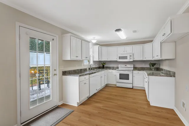 a kitchen with granite countertop white cabinets and white appliances