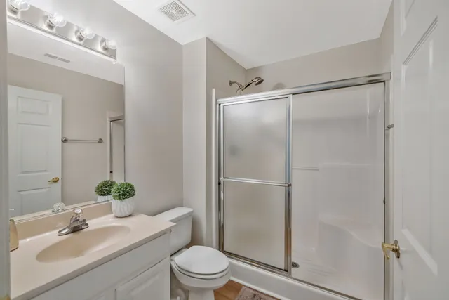 a bathroom with a shower sink vanity mirror and toilet
