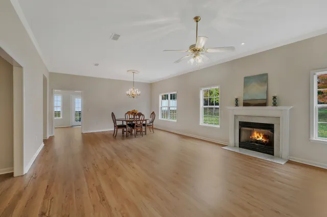 a view of a livingroom with furniture a fireplace wooden floor and chandelier