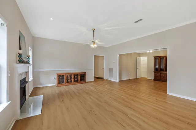 a view of an empty room with wooden floor and a fireplace