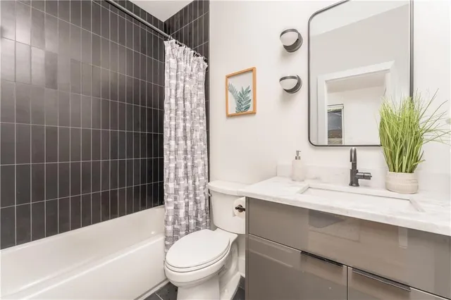 a bathroom with a sink a toilet a mirror a vanity and bathtub