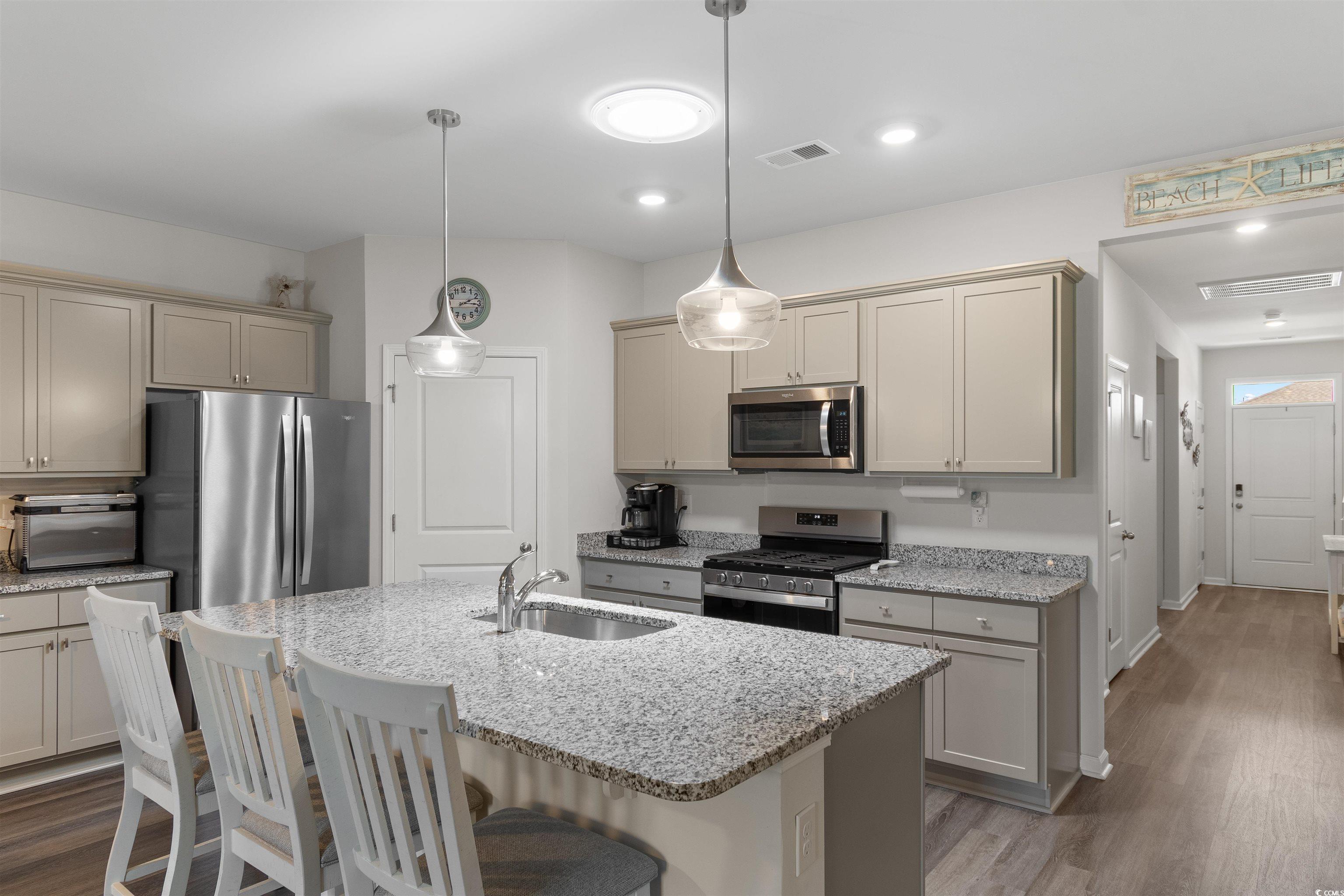 2438 Polaris Path Myrtle Beach, SC 29577 - Photo 8 of 40 Kitchen with stainless steel appliances, wood finished floors, a breakfast bar area, and light stone countertops