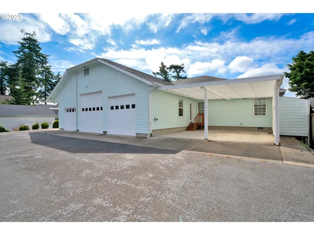 a view of a white house with a yard table and chairs
