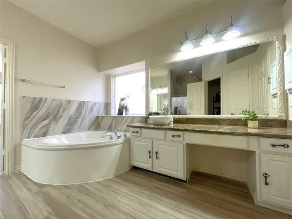 a spacious bathroom with a tub sink and mirror