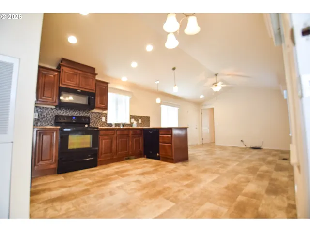 a kitchen with stainless steel appliances kitchen island granite countertop a refrigerator a sink and a stove