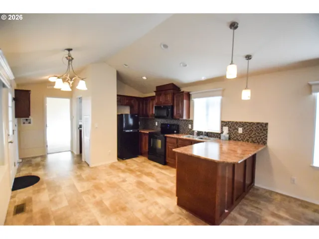 a large kitchen with kitchen island a sink stainless steel appliances and a chandelier