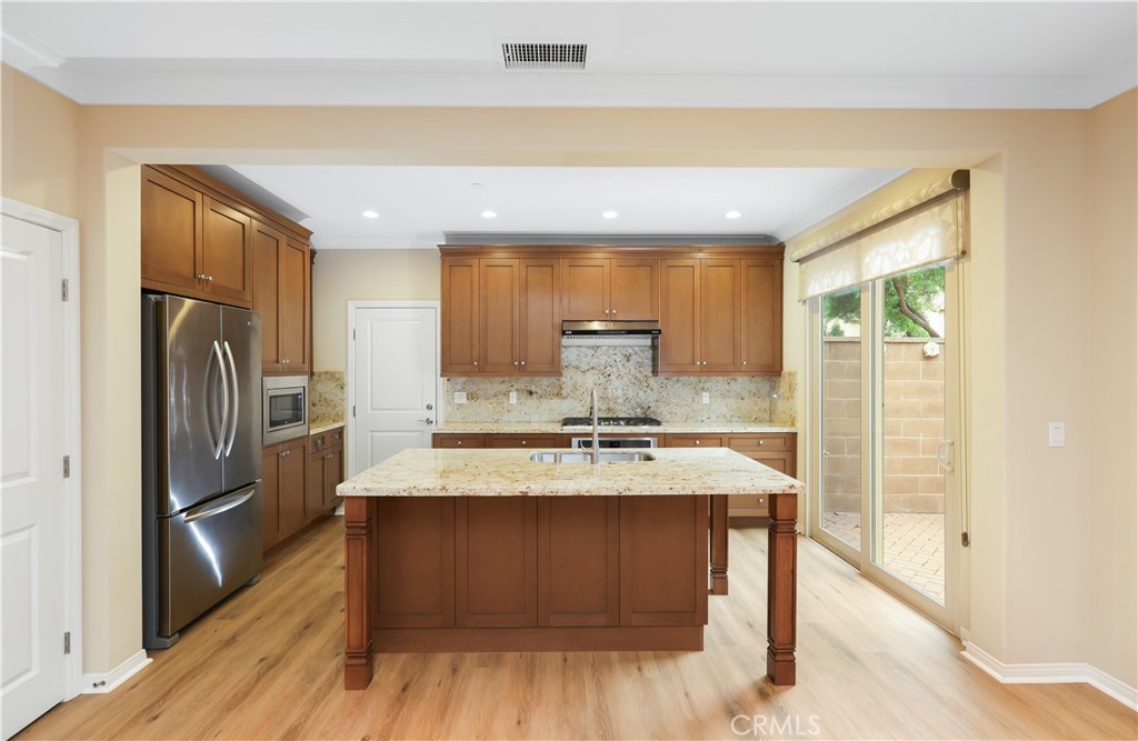 220 Kempton Irvine, CA 92620 - Photo 16 of 42 a kitchen with kitchen island granite countertop wooden cabinets a refrigerator a stove and a sink with wooden floor