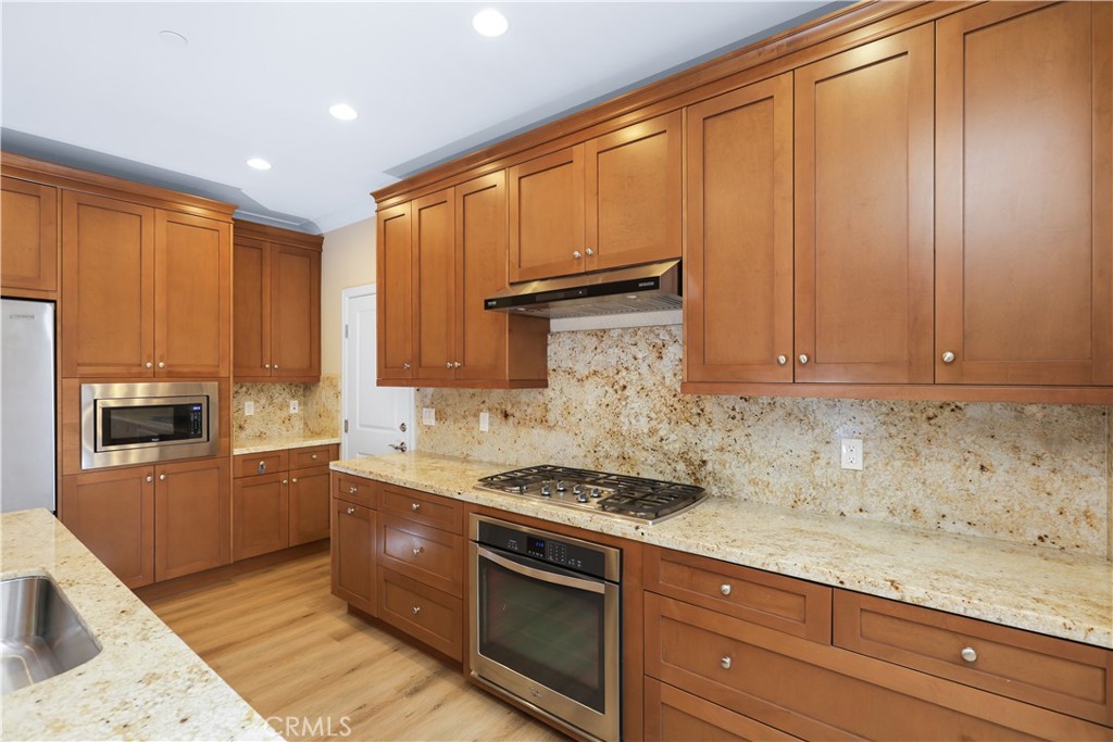 220 Kempton Irvine, CA 92620 - Photo 19 of 42 a kitchen with granite countertop cabinets stainless steel appliances and wooden floor
