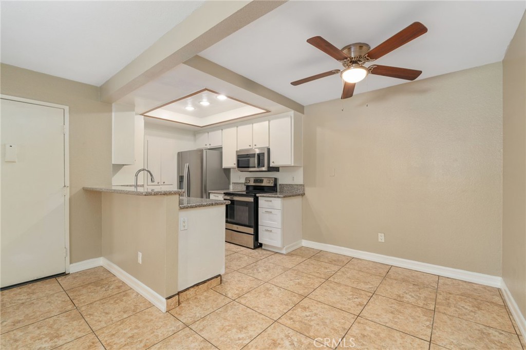 3535 Banbury Drive, Unit 119 Riverside, CA 92505 - Photo 6 of 23 a kitchen with a refrigerator a microwave and white cabinets