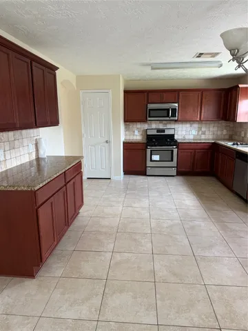 a large kitchen with granite countertop a stove a sink and a microwave