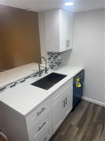 a kitchen with a sink cabinets and wooden floor