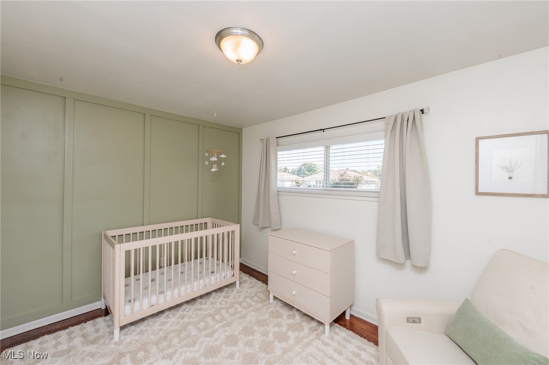 7316 Oakwood Road Parma, OH 44130 - Photo 13 of 41 Bedroom with a decorative wall, a nursery area, and wood finished floors
