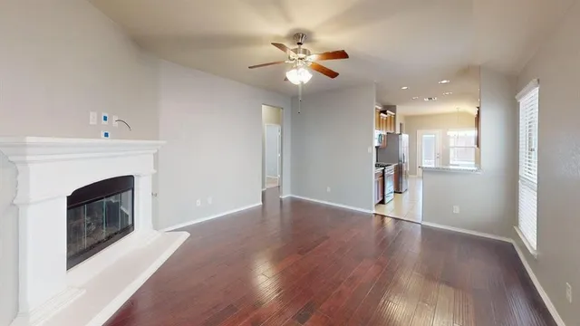 a view of an empty room with wooden floor and a fireplace