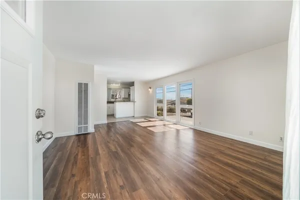 a view of a big room with wooden floor and a kitchen