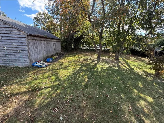 a view of backyard with large tree and wooden fence