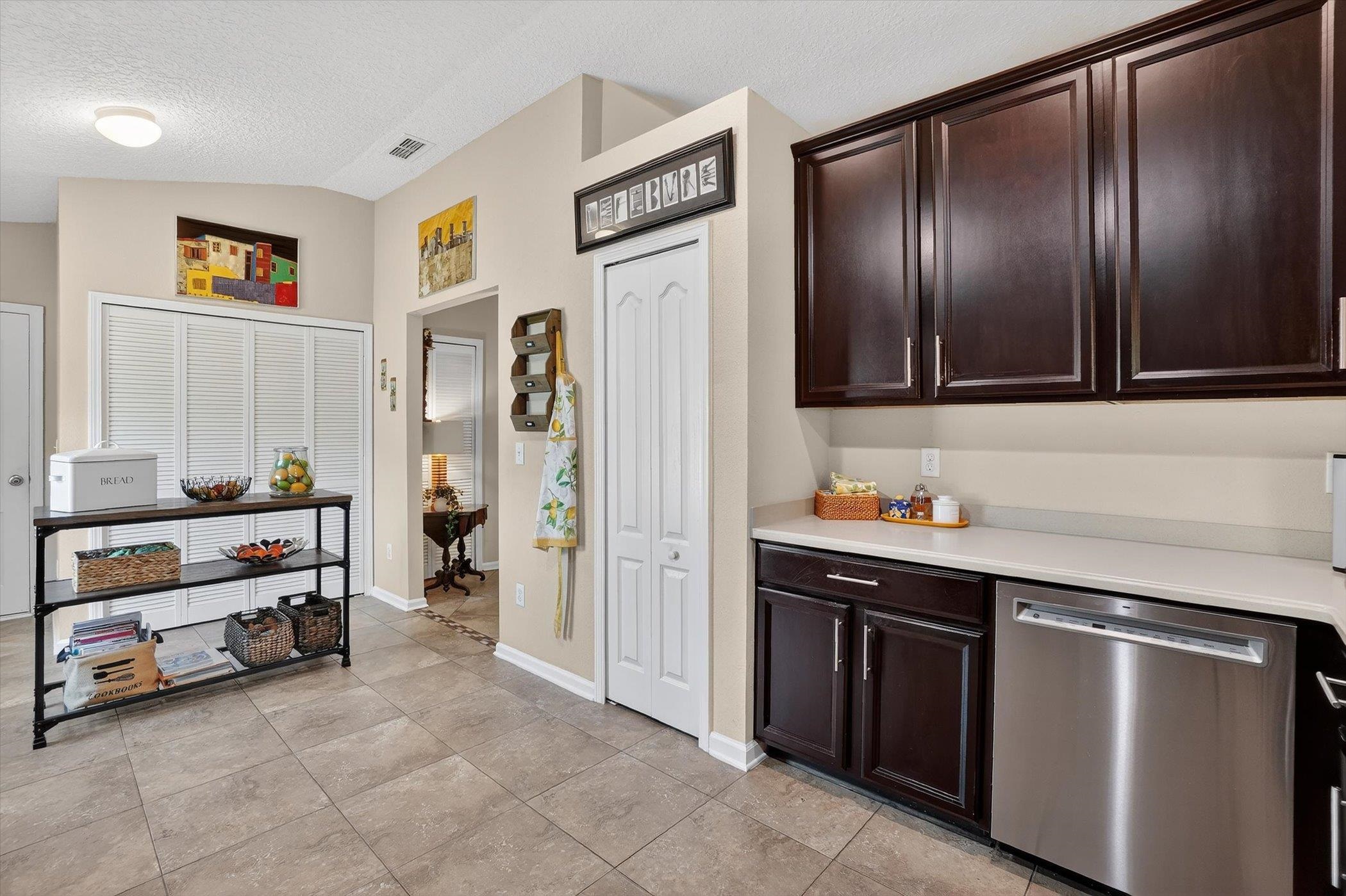 137 Fallen Timber Way St. Augustine, FL 32084 - Photo 17 of 45 Kitchen featuring stainless steel dishwasher, dark wood finish cabinets, light countertops, and light tile patterned floors