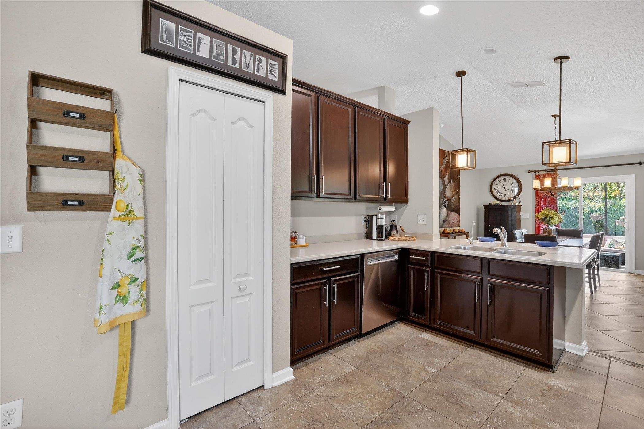 137 Fallen Timber Way St. Augustine, FL 32084 - Photo 18 of 45 Kitchen featuring dark wood finish cabinetry, a peninsula, decorative light fixtures, dishwasher, and lofted ceiling