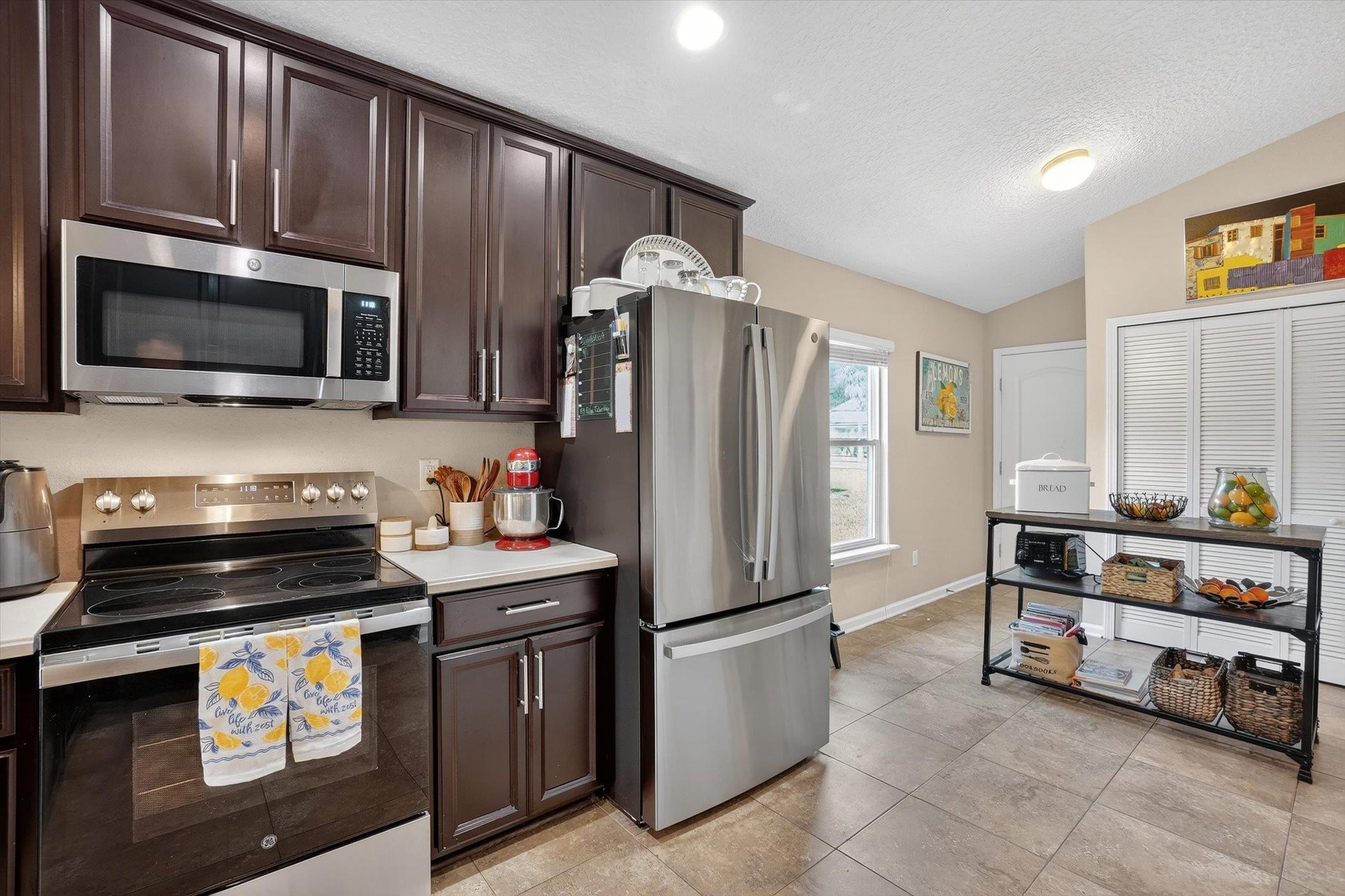 137 Fallen Timber Way St. Augustine, FL 32084 - Photo 20 of 45 Kitchen with dark wood finish cabinets, stainless steel appliances, light countertops, and light tile patterned floors