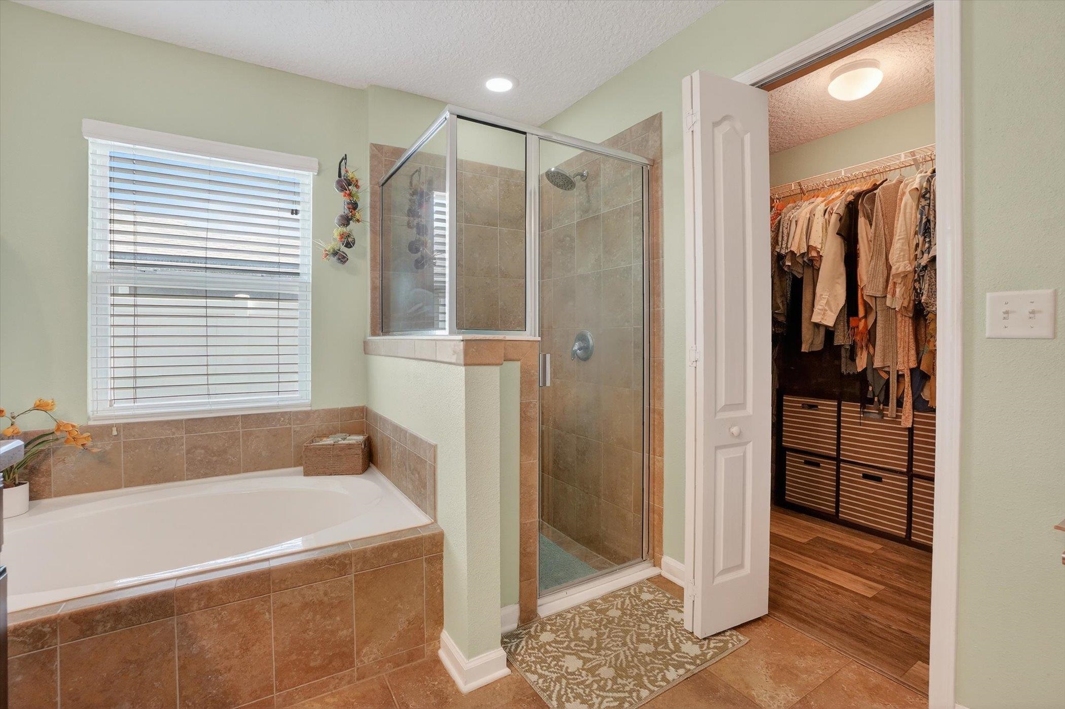 137 Fallen Timber Way St. Augustine, FL 32084 - Photo 25 of 45 Full bath featuring a walk in closet, a shower stall, light tile patterned floors, a textured ceiling, and a bath