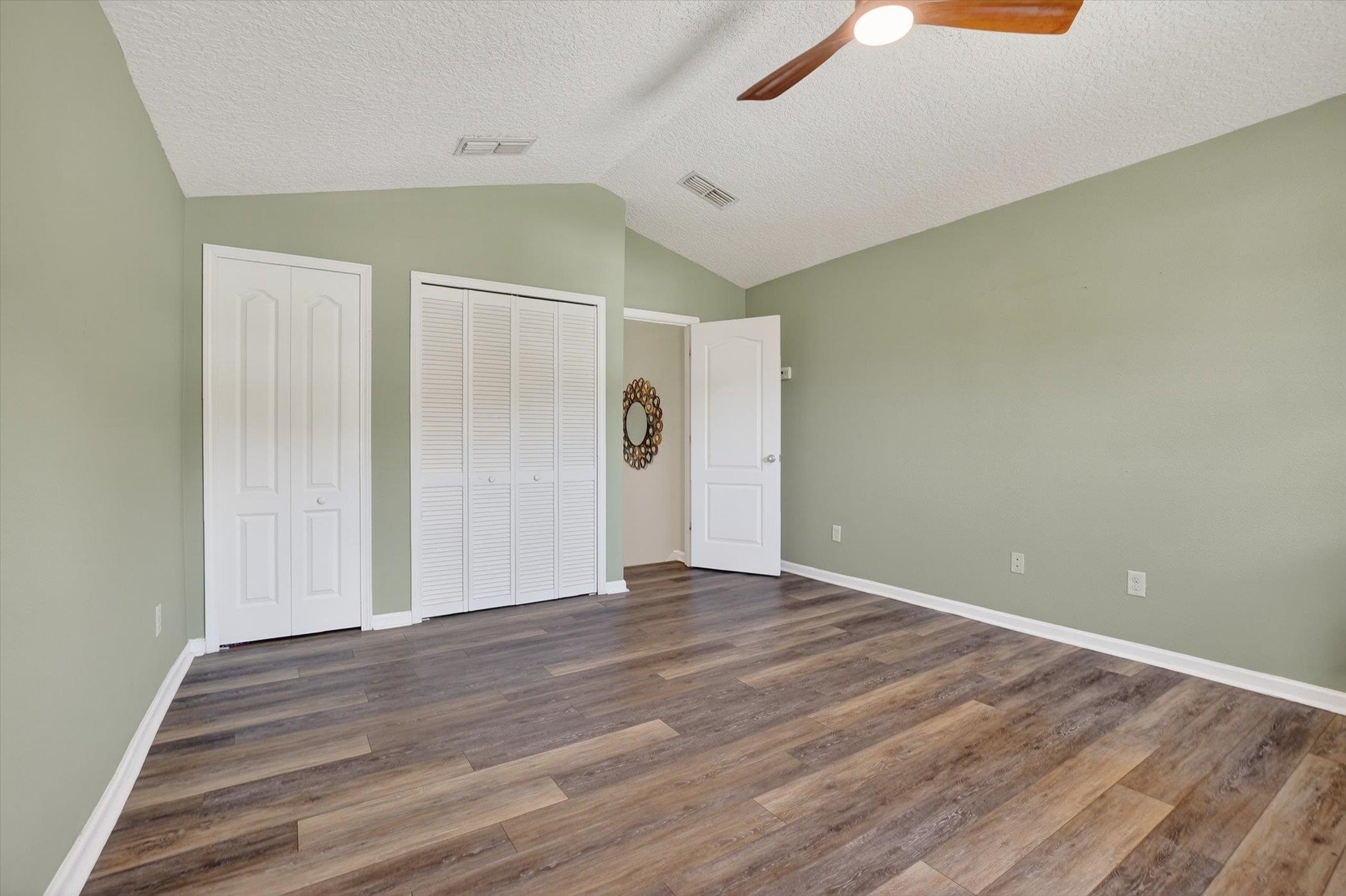137 Fallen Timber Way St. Augustine, FL 32084 - Photo 33 of 45 Unfurnished bedroom with multiple closets, dark wood-style floors, and ceiling fan
