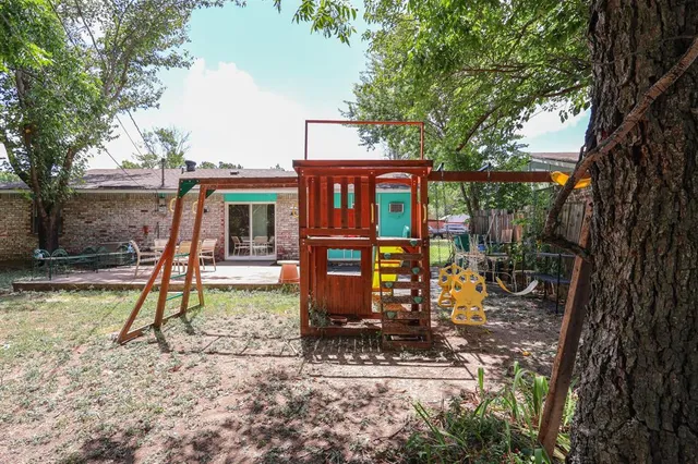 a view of a patio with table and chairs potted plants and large tree