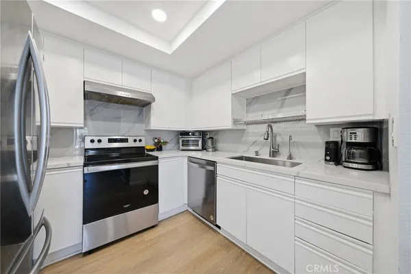 a kitchen with granite countertop white cabinets and stainless steel appliances