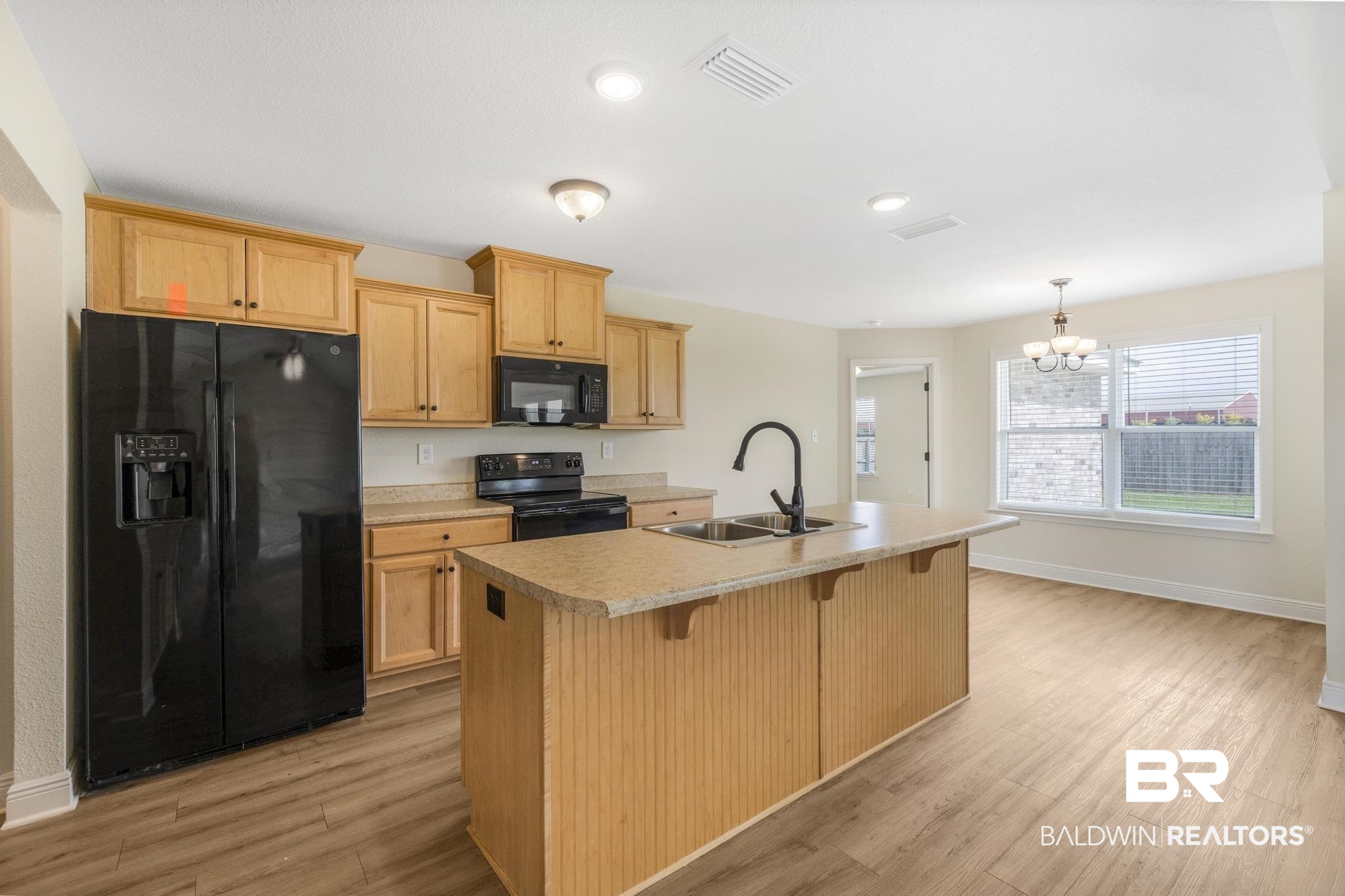 21580 Talbot Lane Robertsdale, AL 36567 - Photo 10 of 25 Kitchen featuring black appliances, a kitchen island with sink, a kitchen bar, light wood-type flooring, and light countertops