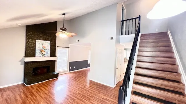 a view of a livingroom with wooden floor fireplace and stairs