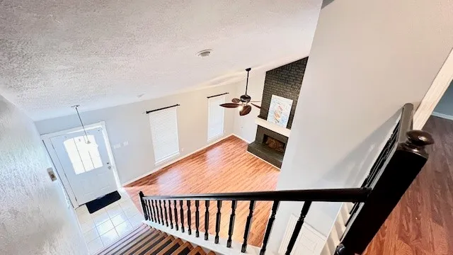 a view of a hallway to a livingroom with wooden floor and stairs