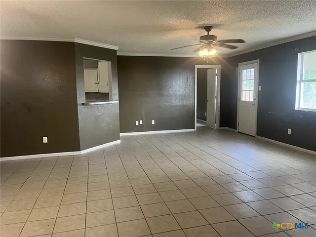 a view of an empty room with window and chandelier fan
