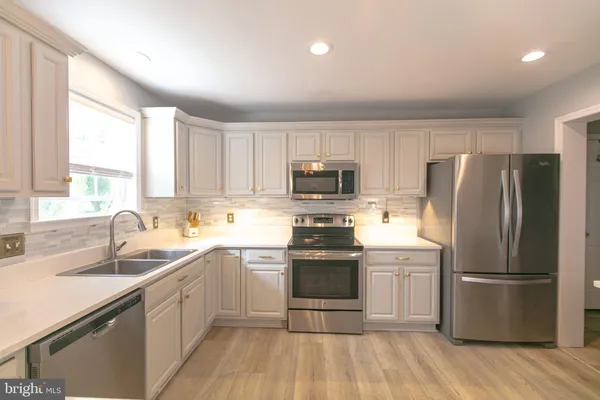 a kitchen with granite countertop a sink dishwasher microwave stove and cabinets