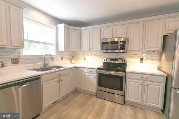 a kitchen with granite countertop white cabinets and stainless steel appliances