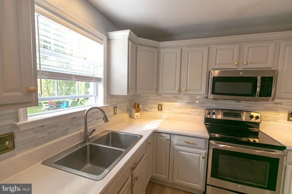 a kitchen with granite countertop stainless steel appliances a stove a sink a refrigerator cabinets and a window