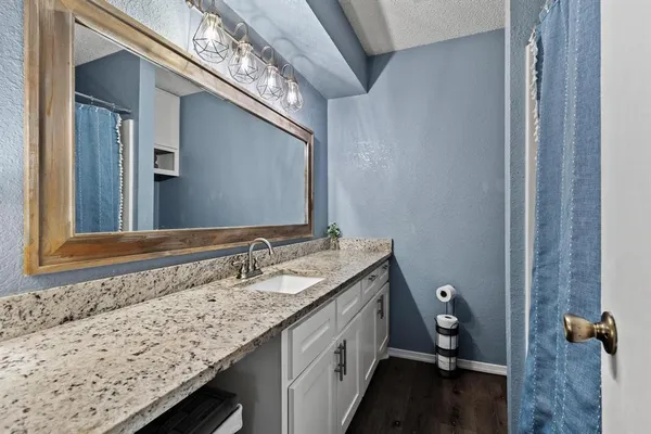 a bathroom with a granite countertop sink and a mirror