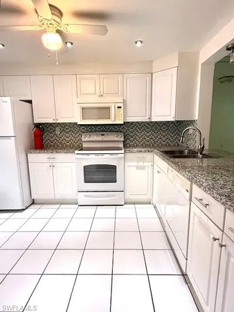 a kitchen with granite countertop a stove a sink and a refrigerator