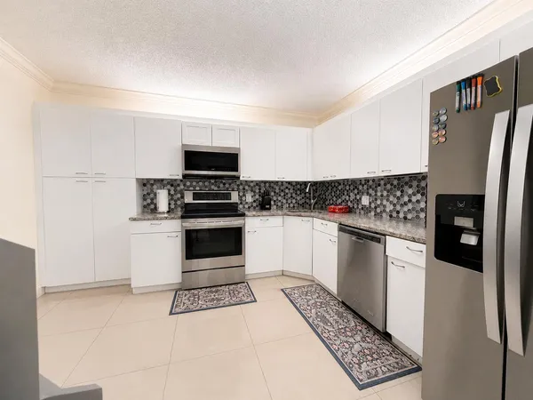 a kitchen with granite countertop a refrigerator and a stove top oven